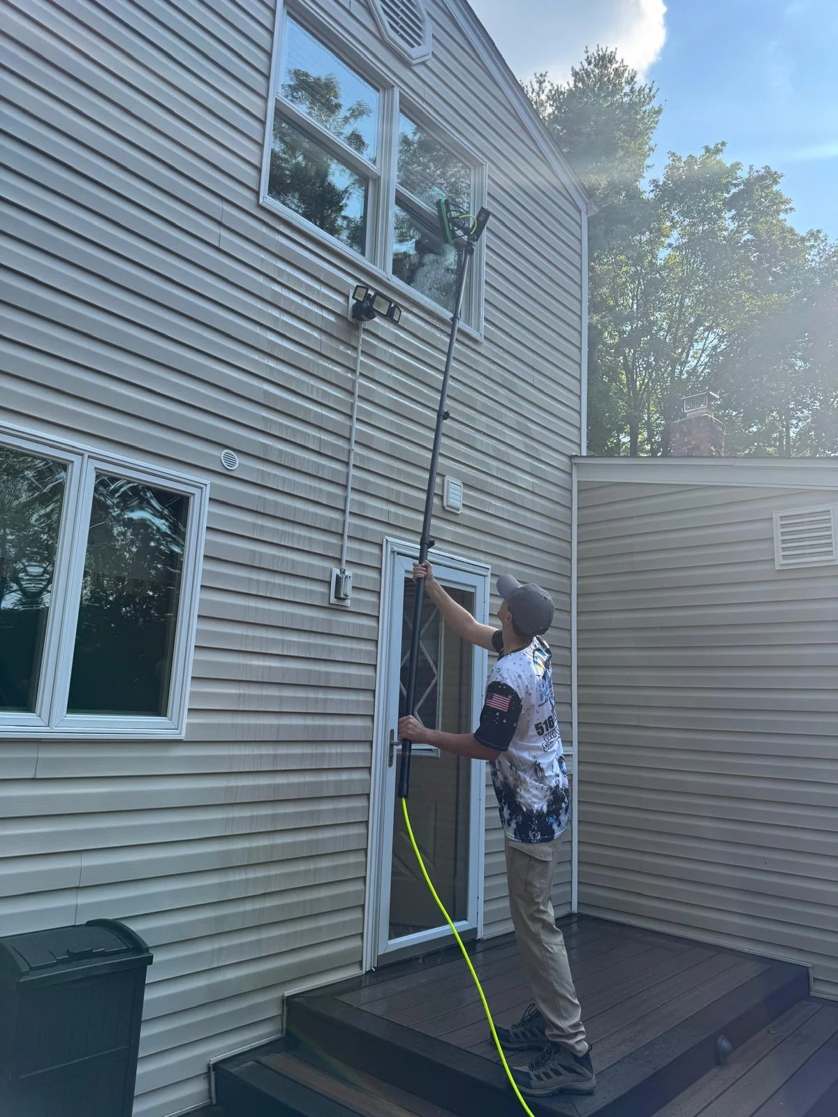 Pure H2O technician using long extension pole to clean second story windows